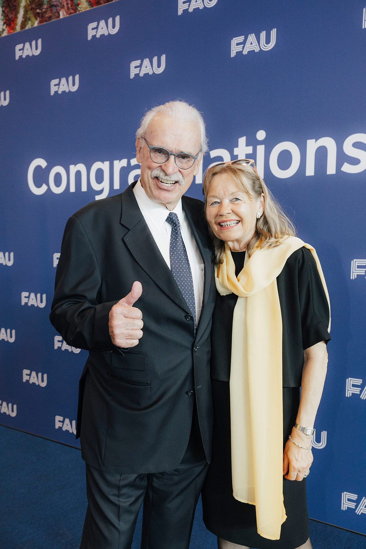 Ein Paar wird vor der Fotowand abgelichtet, der Herr gibt einen 