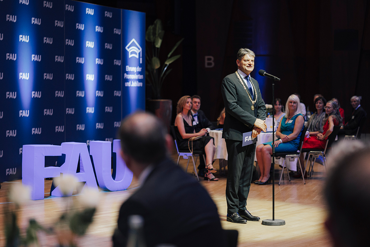 Präsident Hornegger steht auf der Bühne vor dem Mikrofon und spricht.