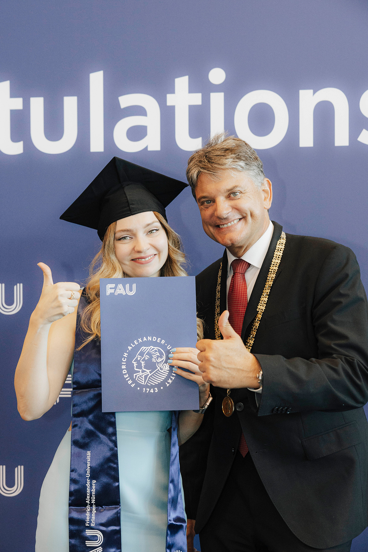 Präsident Hornegger posiert mit einer Jubilarin und ihrer Urkunde vor der Fotowand.