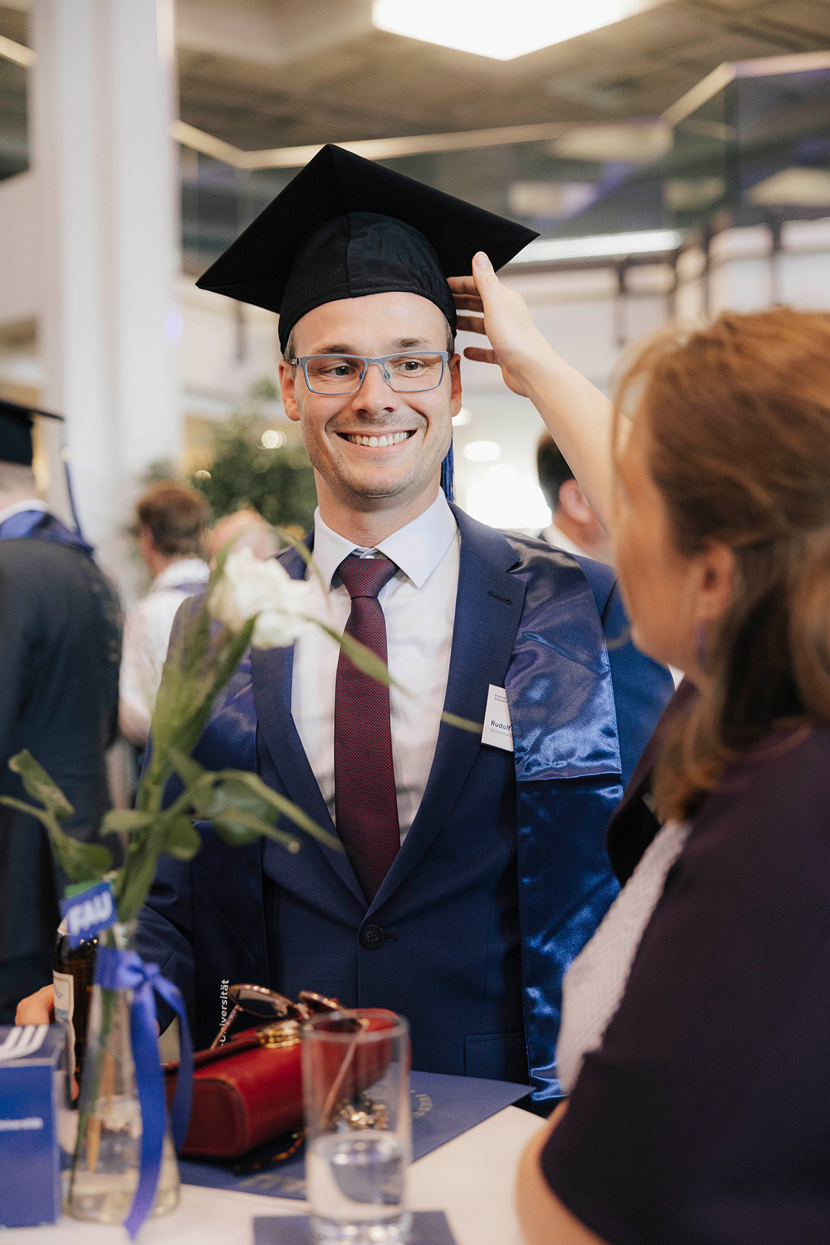 Ein Jubilar in Festkleidung am Stehtisch im Gespräch.