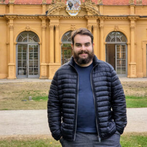 Ein braunhaariger, bärtiger Mann steht vor der Orangerie im Schlossgarten