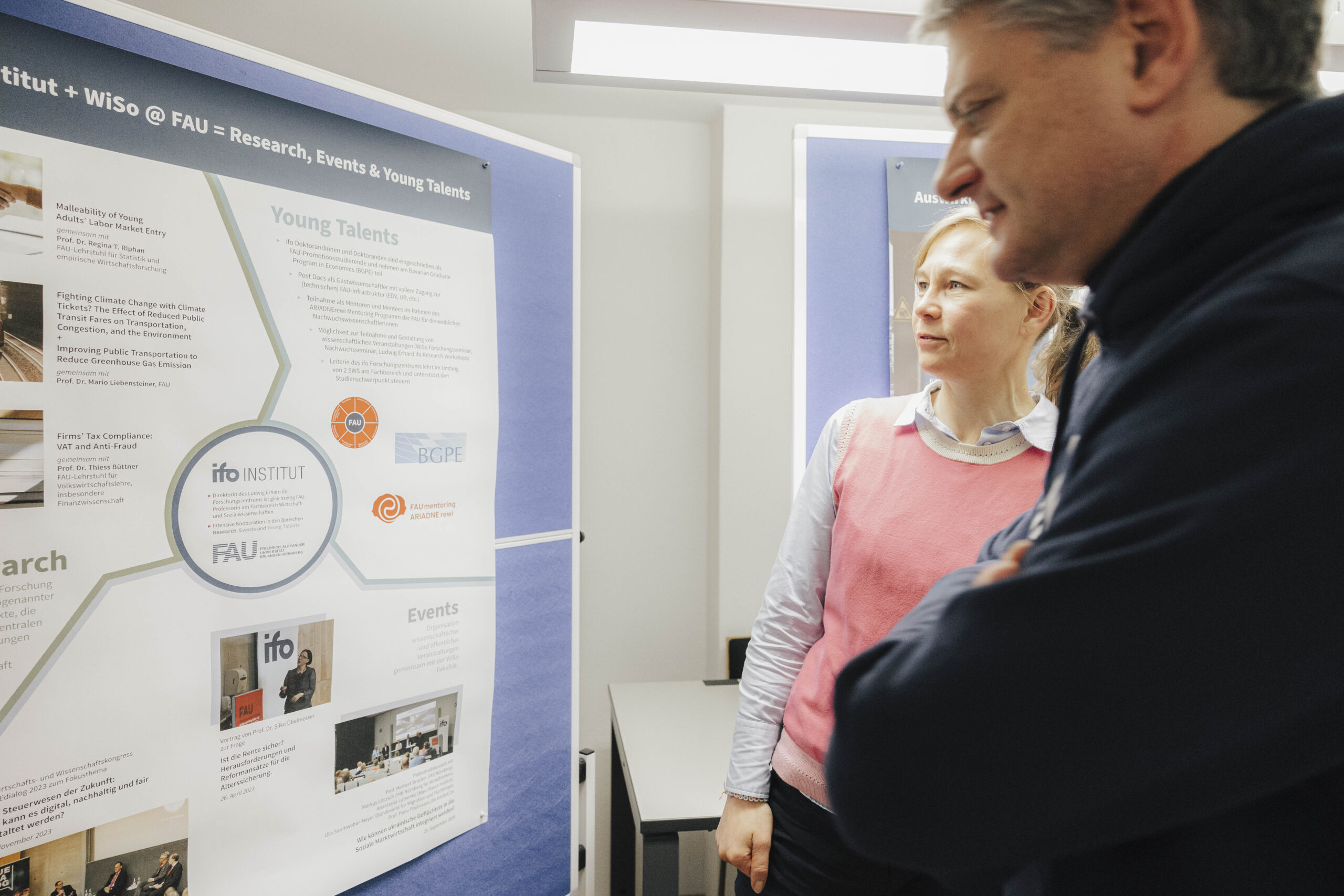 Der FAU-Präsident Hornegger und Prof. Necker stehen vor einer Pinnwand und unterhalten sich.