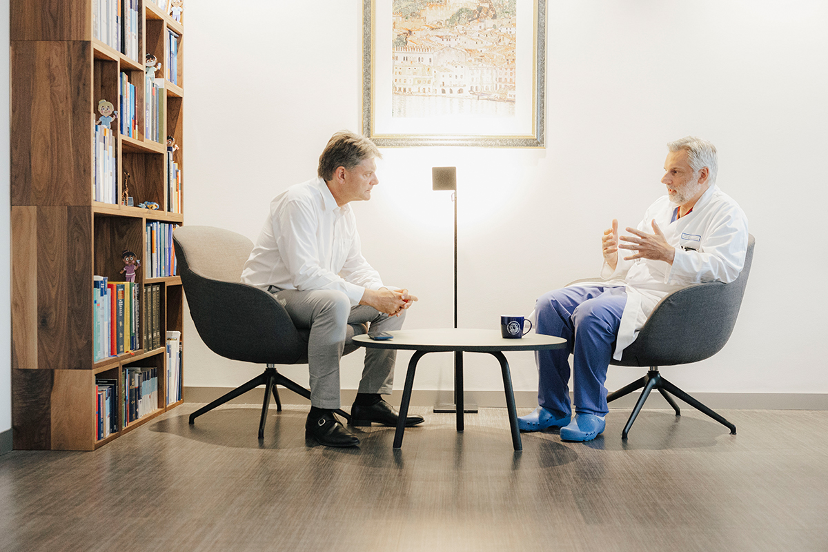 Prof. Dr. Oliver Schnell, LS Neurochirurgie, und Joachim Hornegger sitzen sich an einem Tisch gegenüber und reden gemeinsam.