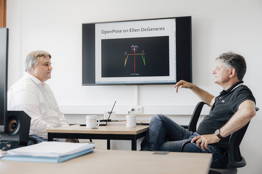 Peter Uhrig und Joachim Hornegger sitzen zusammen an einem Tisch und reden.