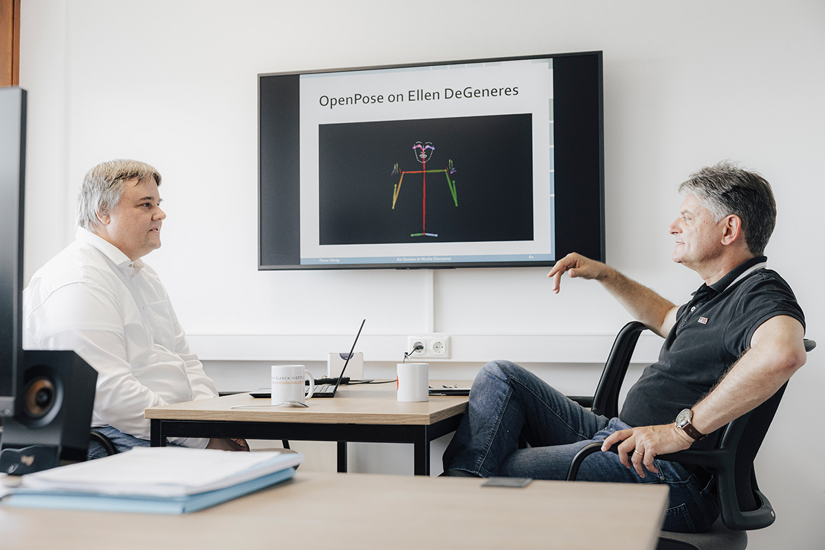 Peter Uhrig und Joachim Hornegger sitzen zusammen an einem Tisch und reden.