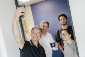 Prof. Peter Uhrig und sein Team posieren gemeinsam mit Präsident Hornegger für ein Selfie.