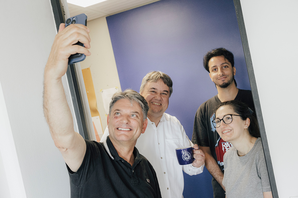 Prof. Peter Uhrig und sein Team posieren gemeinsam mit Präsident Hornegger für ein Selfie.