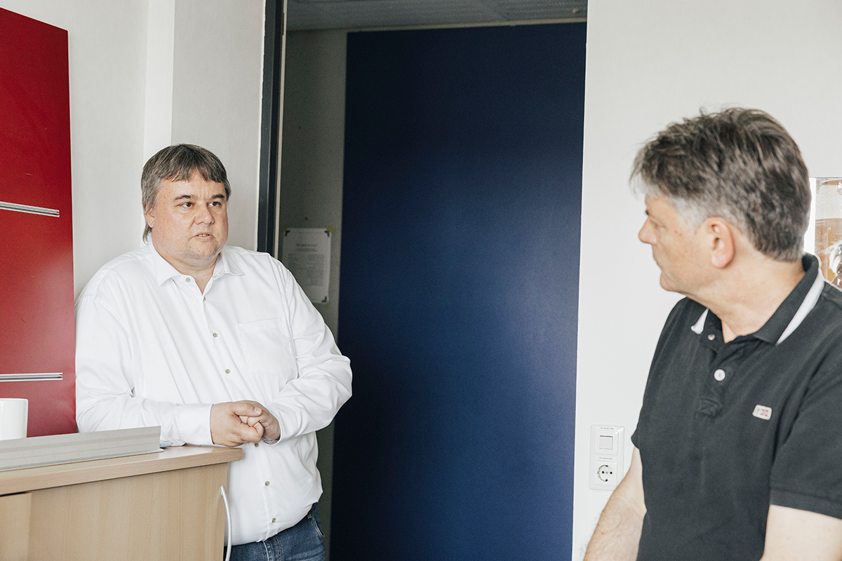 Prof. Uhrig und Präsident Hornegger stehen zusammen in einem Raum und unterhalten sich, Hornegger steht mit dem Rücken zum Betrachter.