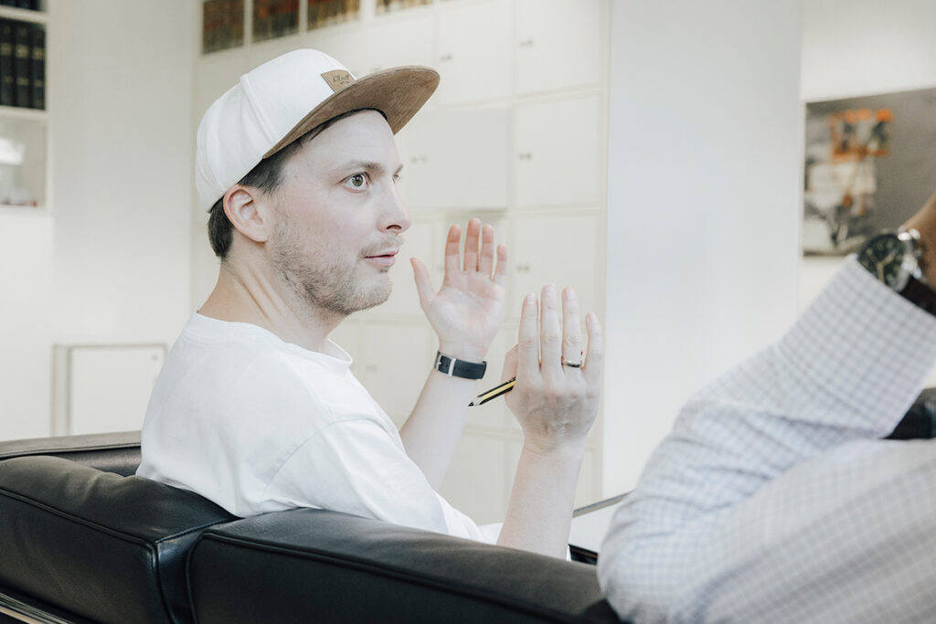 Prof. Reif ist im Seitenprofil zu sehen. Er hat die Hände erhoben, während er etwas erklärt. Er schaut auf eine Person, die im Bild nicht sichtbar ist.