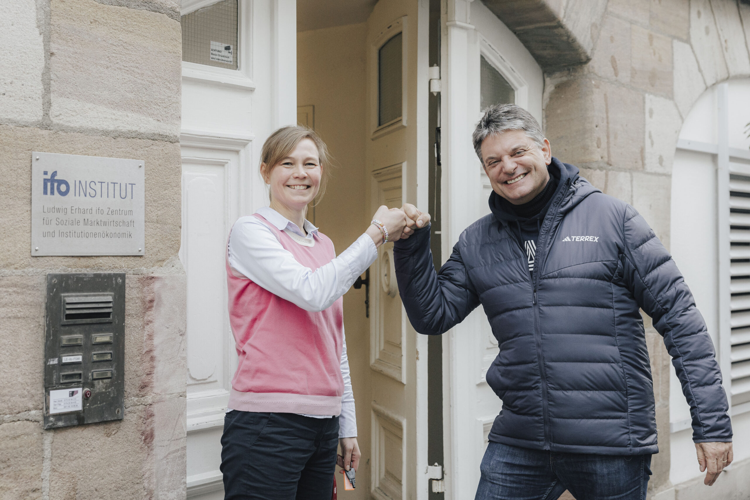 Prof. Necker und Präsident Hornegger stehen vor dem ifo Zentrum und machen einen Handschlag.