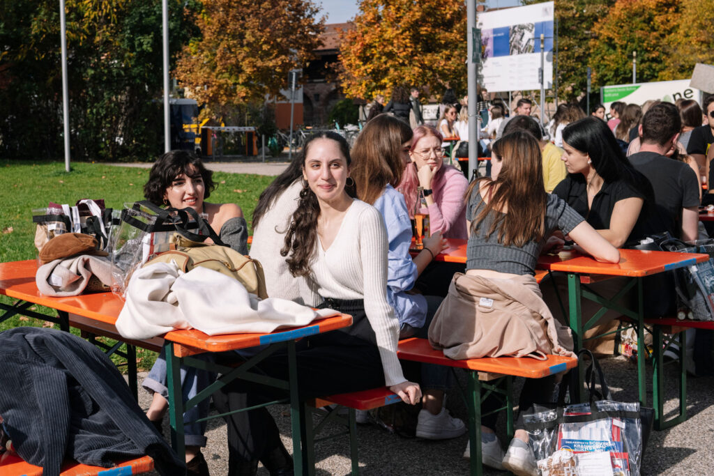 Studierende sitzen an einer Bierbank vor der Wiso