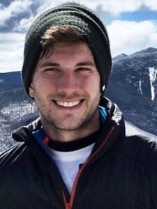 Porträtbild von lächelndem Mann in schneebedeckten Bergen