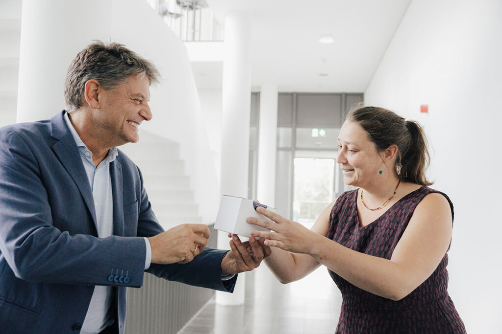 Prof. Hutter und Hornegger stehen gemeinsam in einem hellen Flur, Präsident Hornegger überreicht eine Tasse an Prof. Hutter.