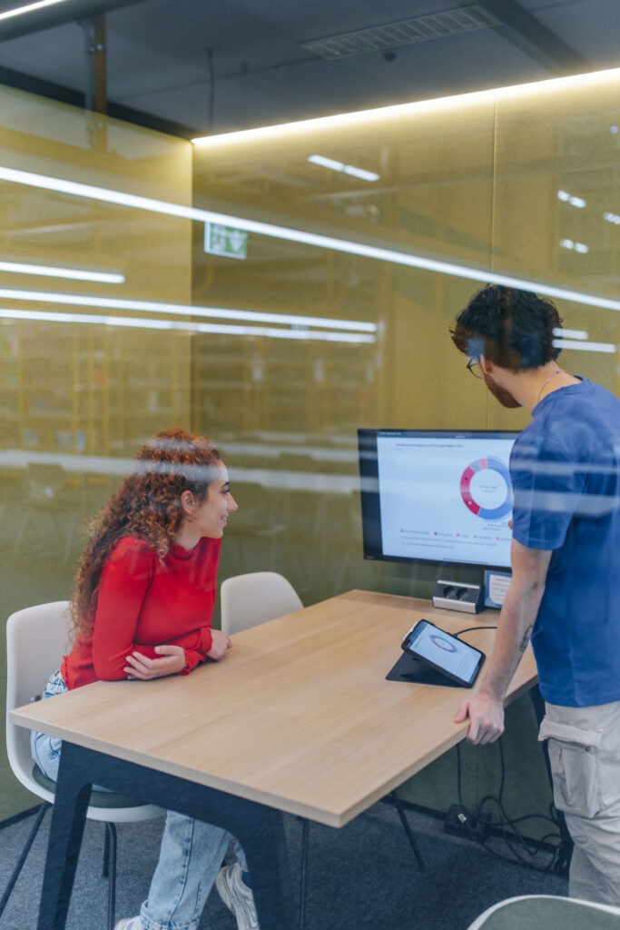 Zwei Studierende schauen auf einen Bildschirm.