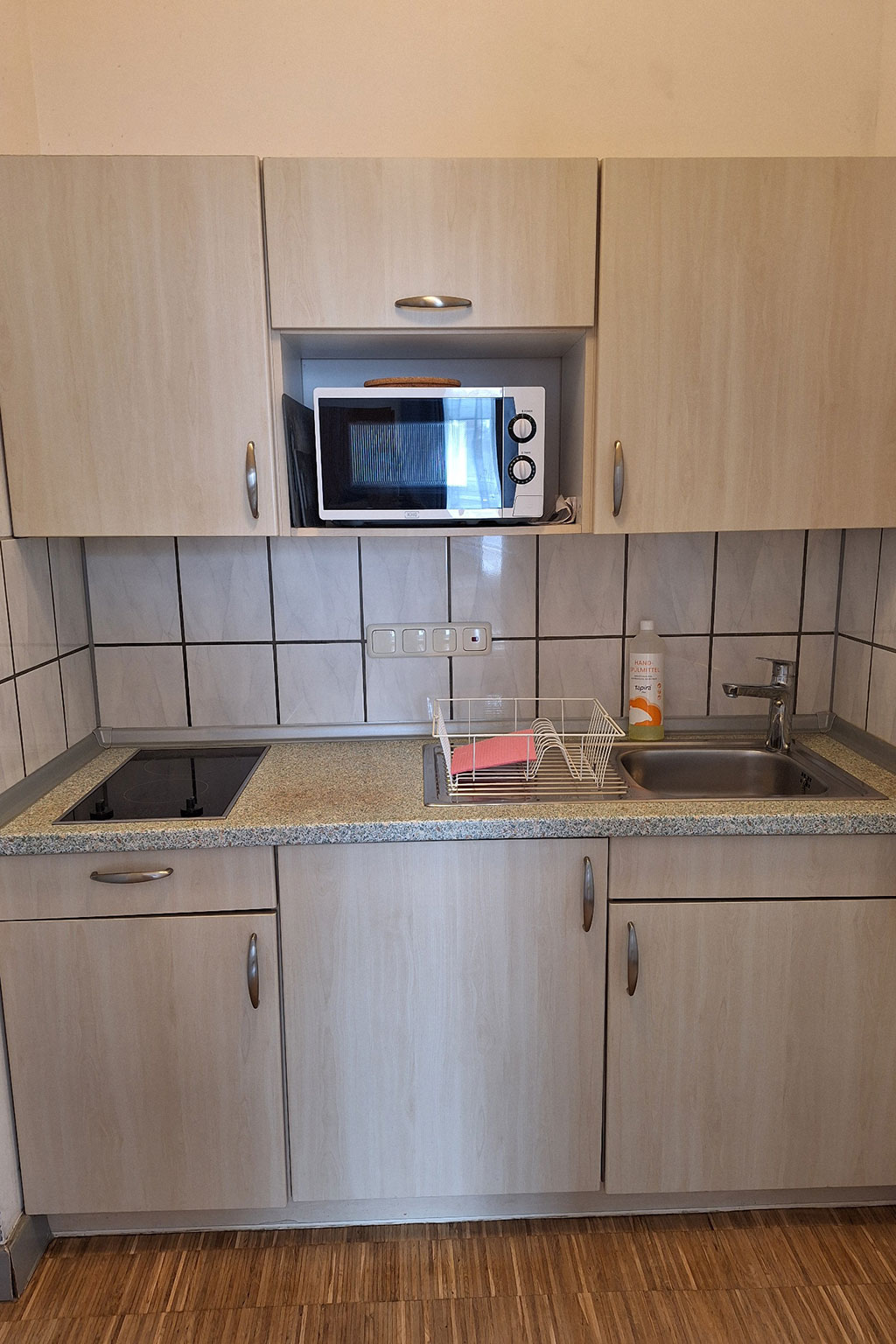 View of a kitchen with microwave, cooktop and sink.