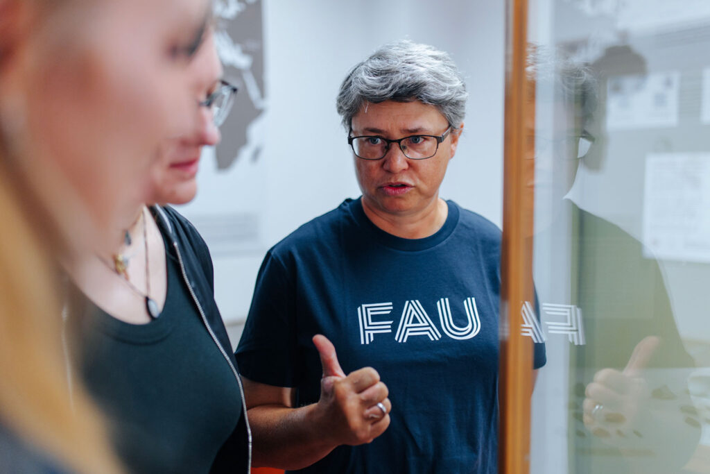 Eine Frau mit FAU-Shirt redet mit zwei weiteren Frauen.