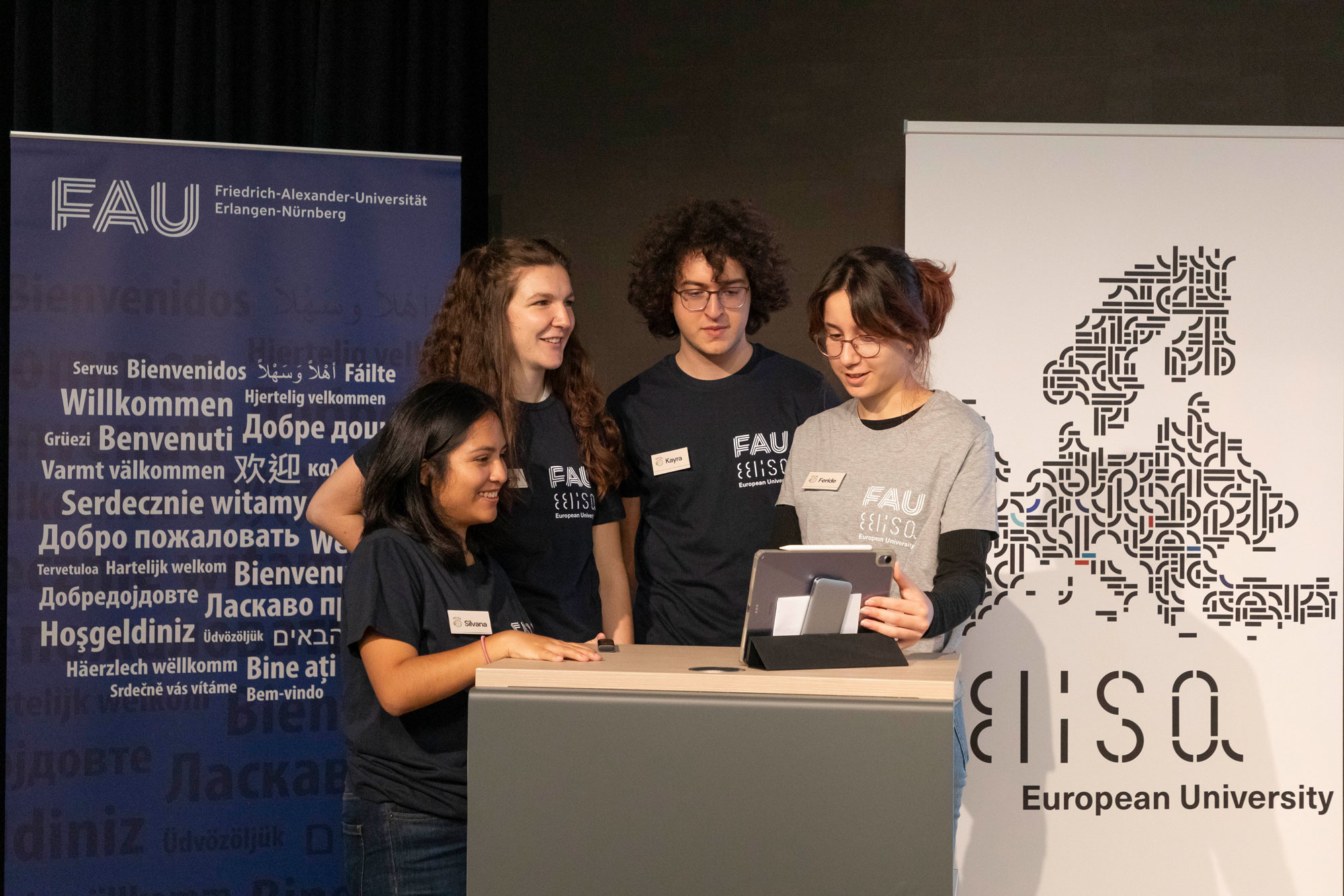 Vier Studierende stehen an einem Rednerpult