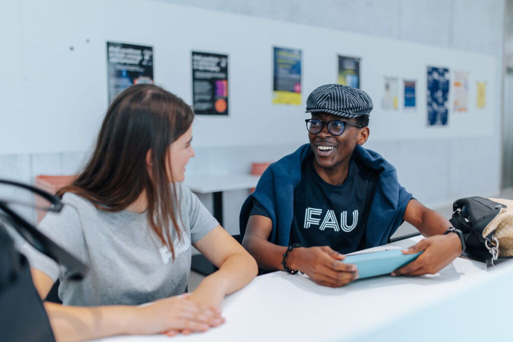 Studentin und Student sitzen am Tisch und unterhalten sich