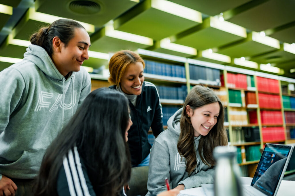 Studierende schauen auf einen Laptop.