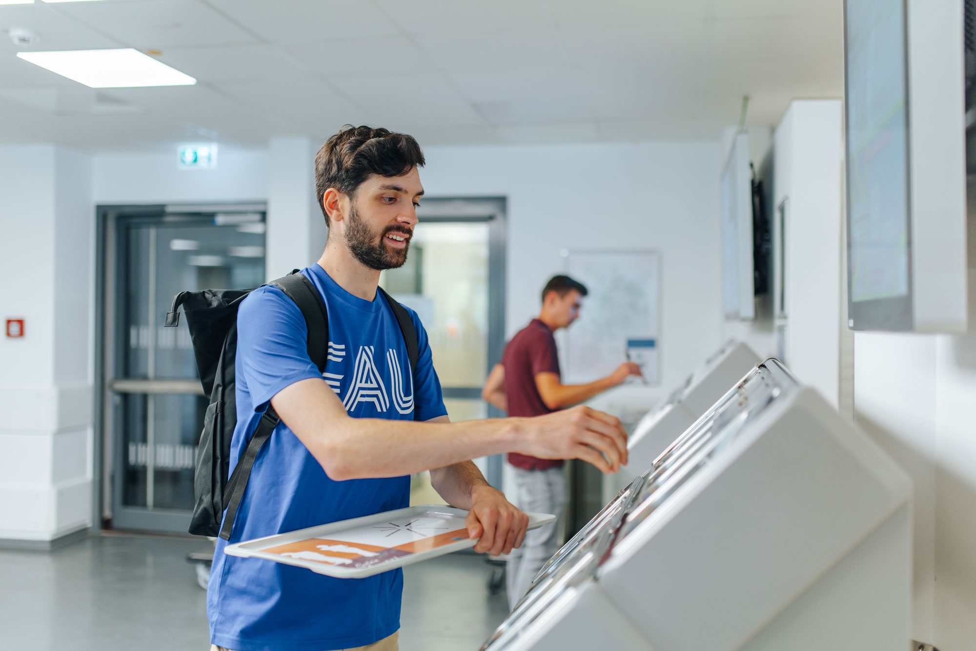 Mann holt sich in der Mensa das Besteck.