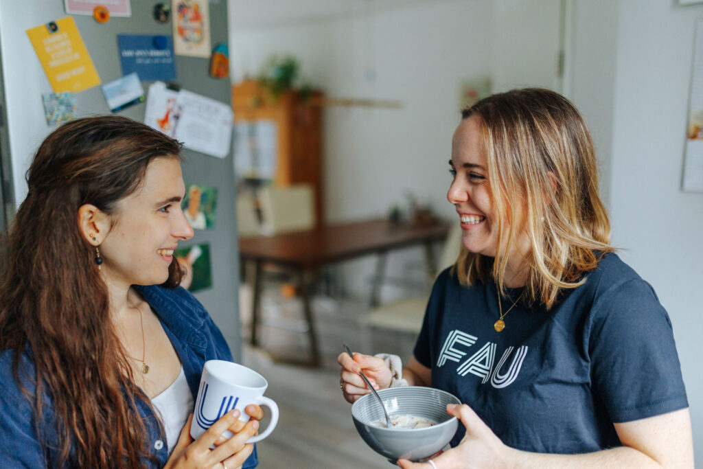 Zwei Frauen unterhalten sich mit Kaffeetasse und Müslischale in der Hand