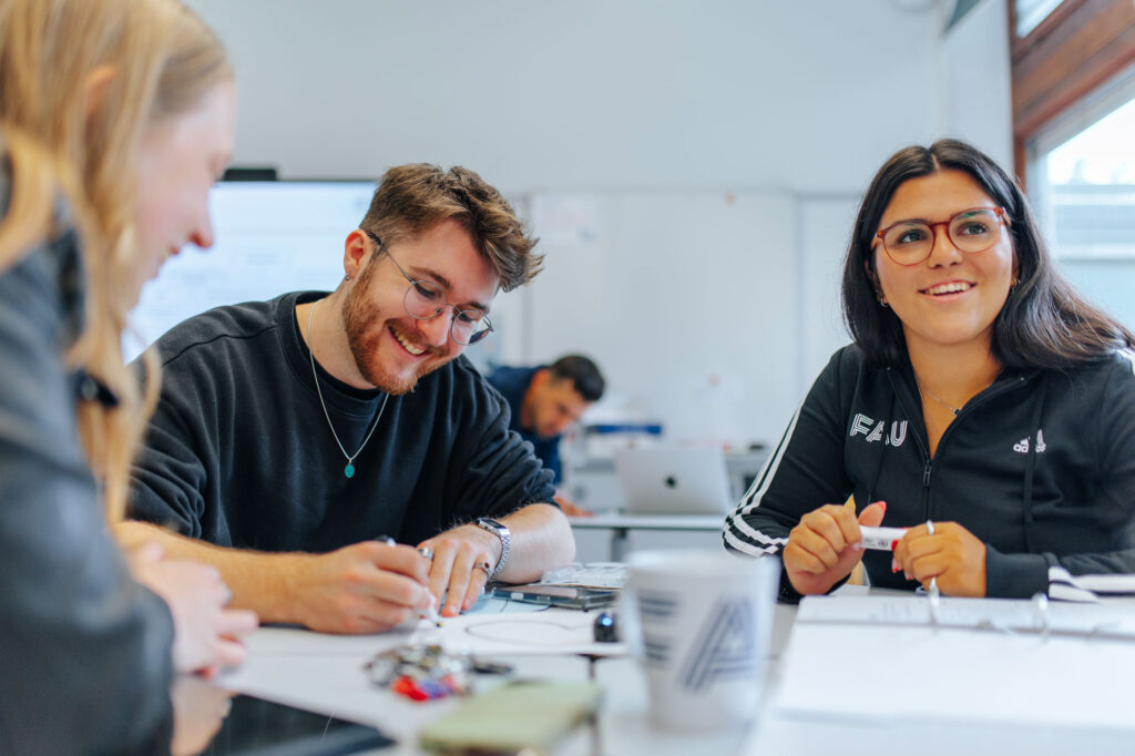 Gruppe von Studierenden sitzt am Tisch und lernt zusammen.