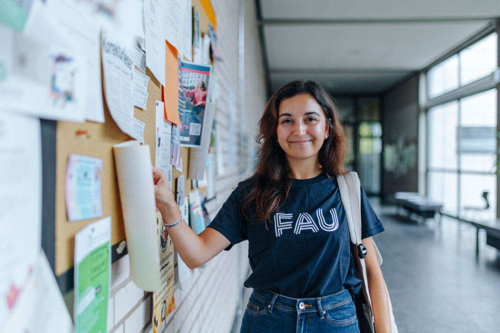 Studentin zeigt auf Pinnwand.