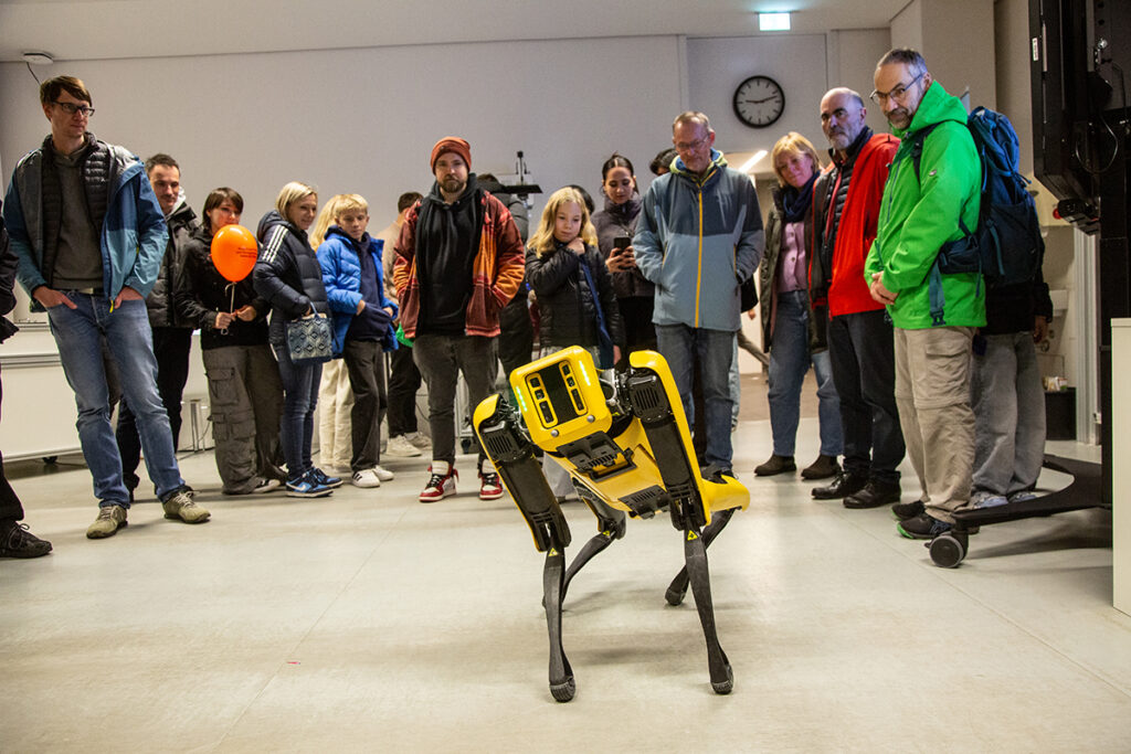 Viele Personen schauen auf einen Roboterhund.