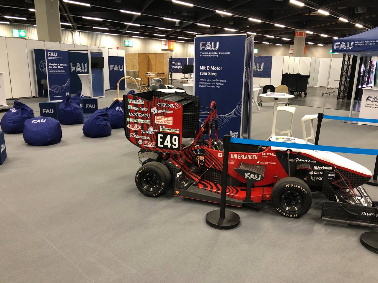 Der FAU-Stand auf der Messe Consumenta in Nürnberg 2024 zeigt ein FAU-Rennauto und FAU-Sitzsäcke
