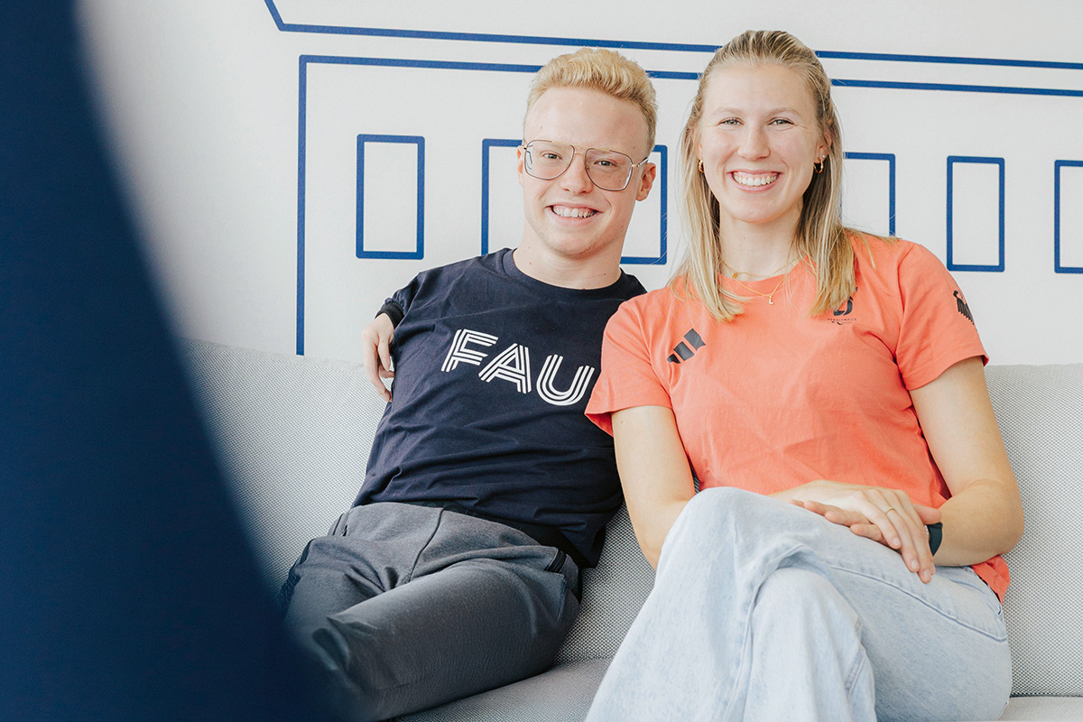 Josia Topf ein junger Mann mit blonden Haaren und Brille, und Lilly Sellak, eine junge frau mit blonden Haaren, sitzen gemeinsam auf einer Couch.
