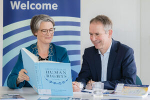 Katrin Kinzelbach und Markus Krajewski schauen in ein Buch über Menschenrechte.