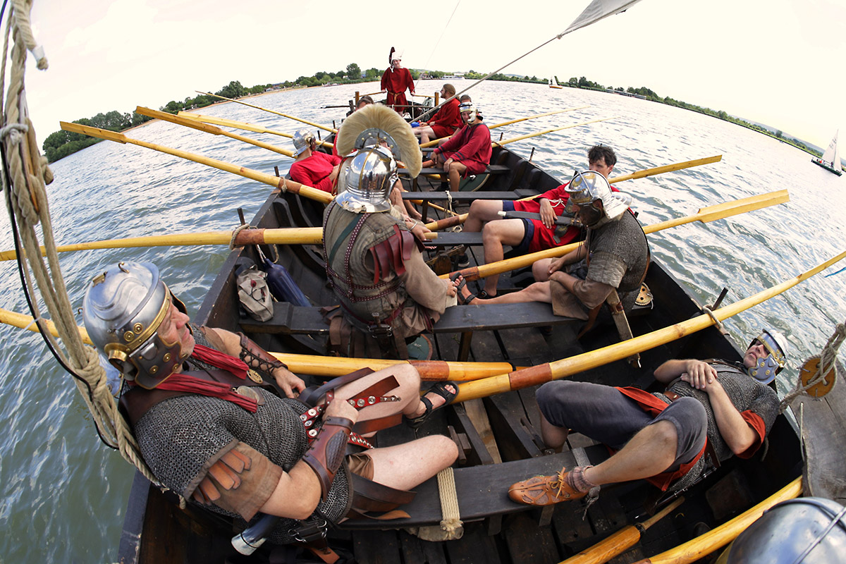 In einem Römerboot sitzen als römische Soldaten verkleidete Männer.