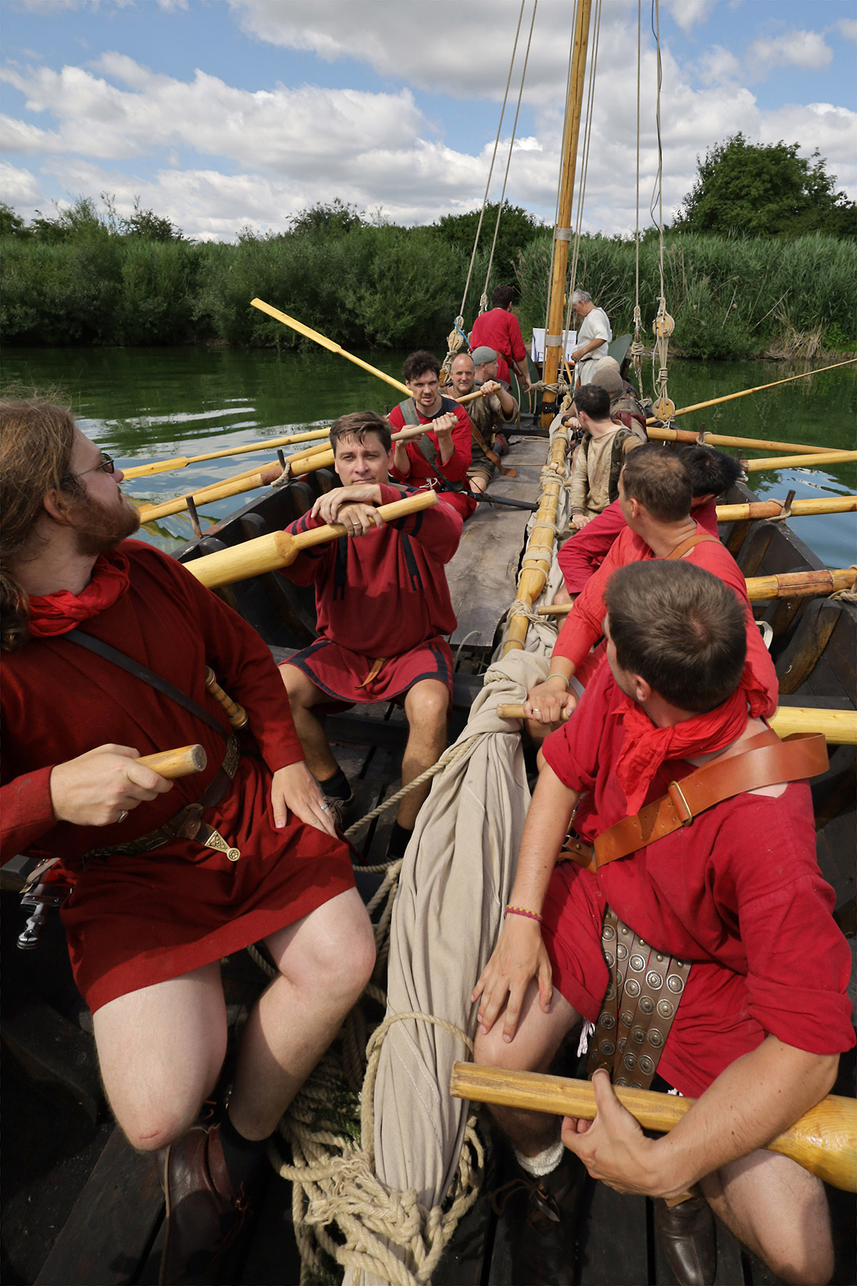 Mehrere Männer in roten Tunikas am Ruder.