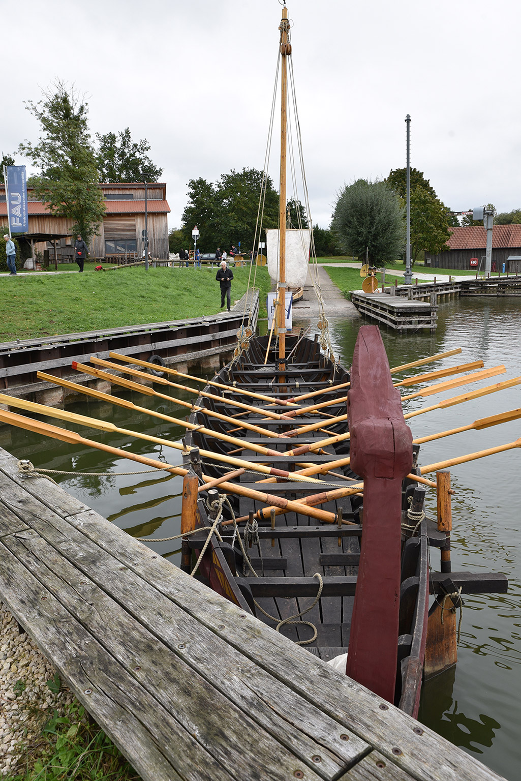 Ein Römerboot liegt im Wasser an einem Steg.