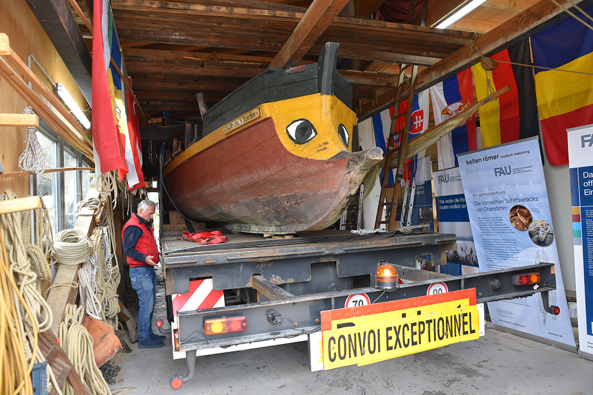 Ein Römerboot auf einem LKW-Anhänger in einer Garage.