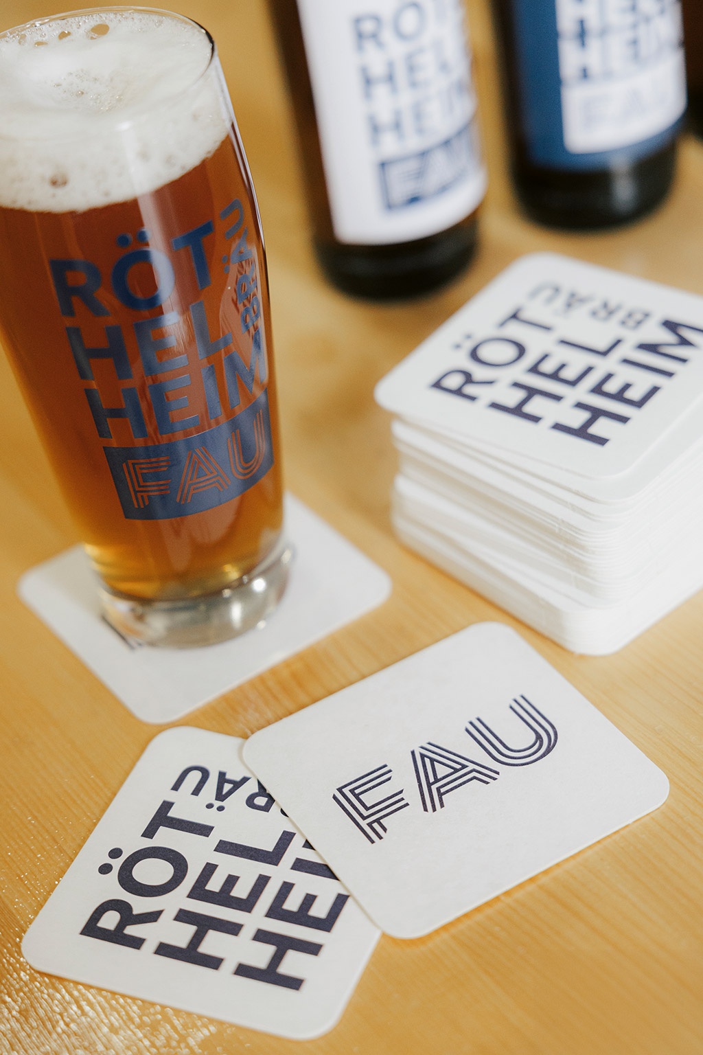 Ein Glas Bier, Bierflaschen und Bierdeckel.