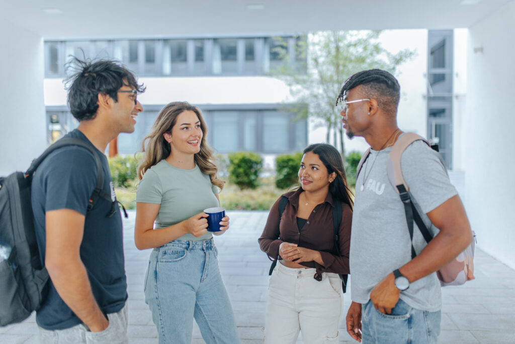 Vier Studierende besprechen sich gemeinsam in einem Innenhof.