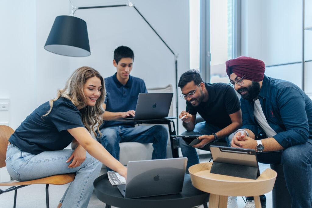 Vier Personen arbeiten zusammen an mehreren Laptops.