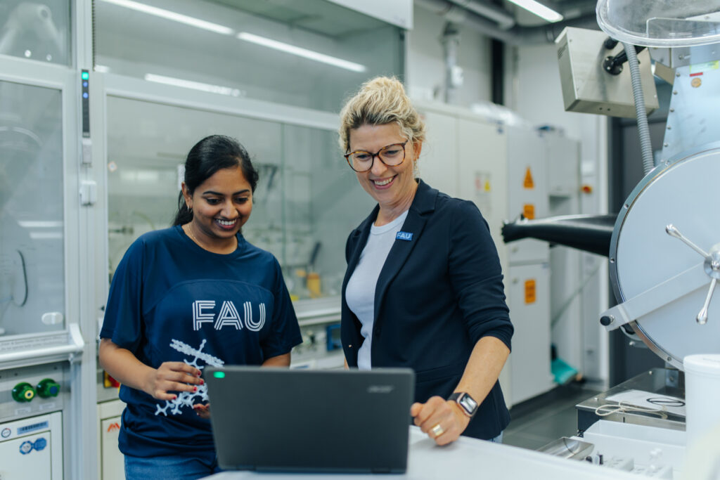 Zwei Personen stehen in einem Labor und schauen in ein Laptop.