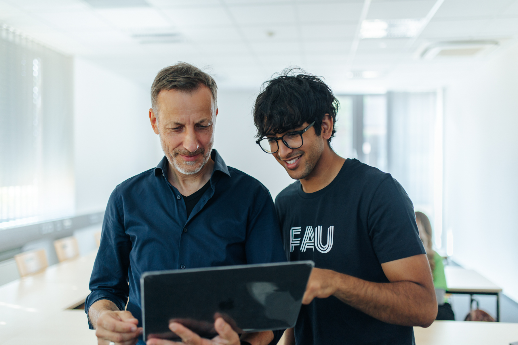 Zwei Männer schauen zusammen auf ein Tablet