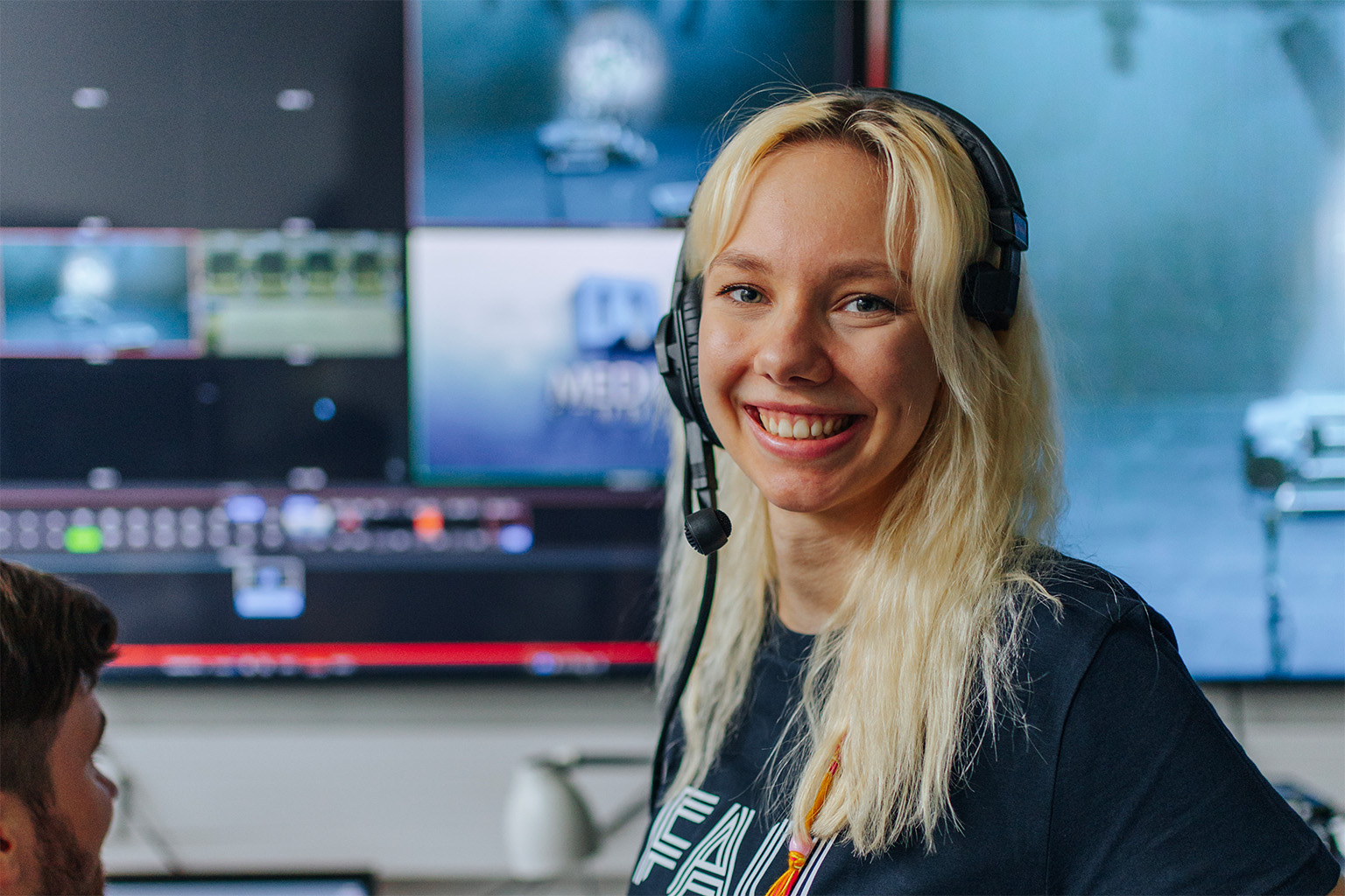Frau mit Headset vor Monitoren