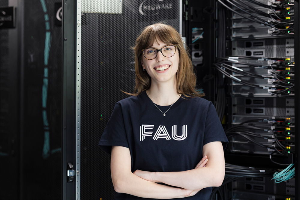 Frau mit FAU-Logo-Shirt vor Rechnern