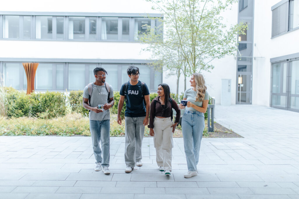 Vier Personen laufen nebeneinander her und unterhalten sich freundlich