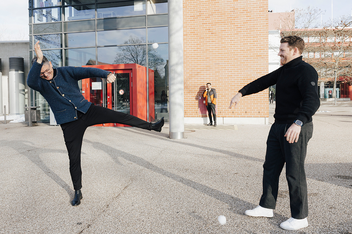 President Hornegger and Professor Nipper are standing in the Wiso courtyard, having a snowball fight. Nipper is on the right, throwing the snowball – Hornegger is on the left, ducking away.
