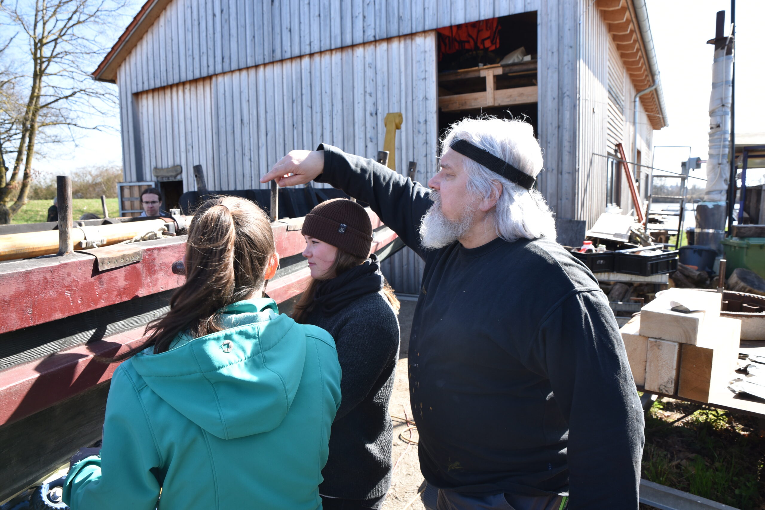FAU chemist Dr. Marcus Speck explains the features of the encaustic paintwork to students Jule and Katharina.