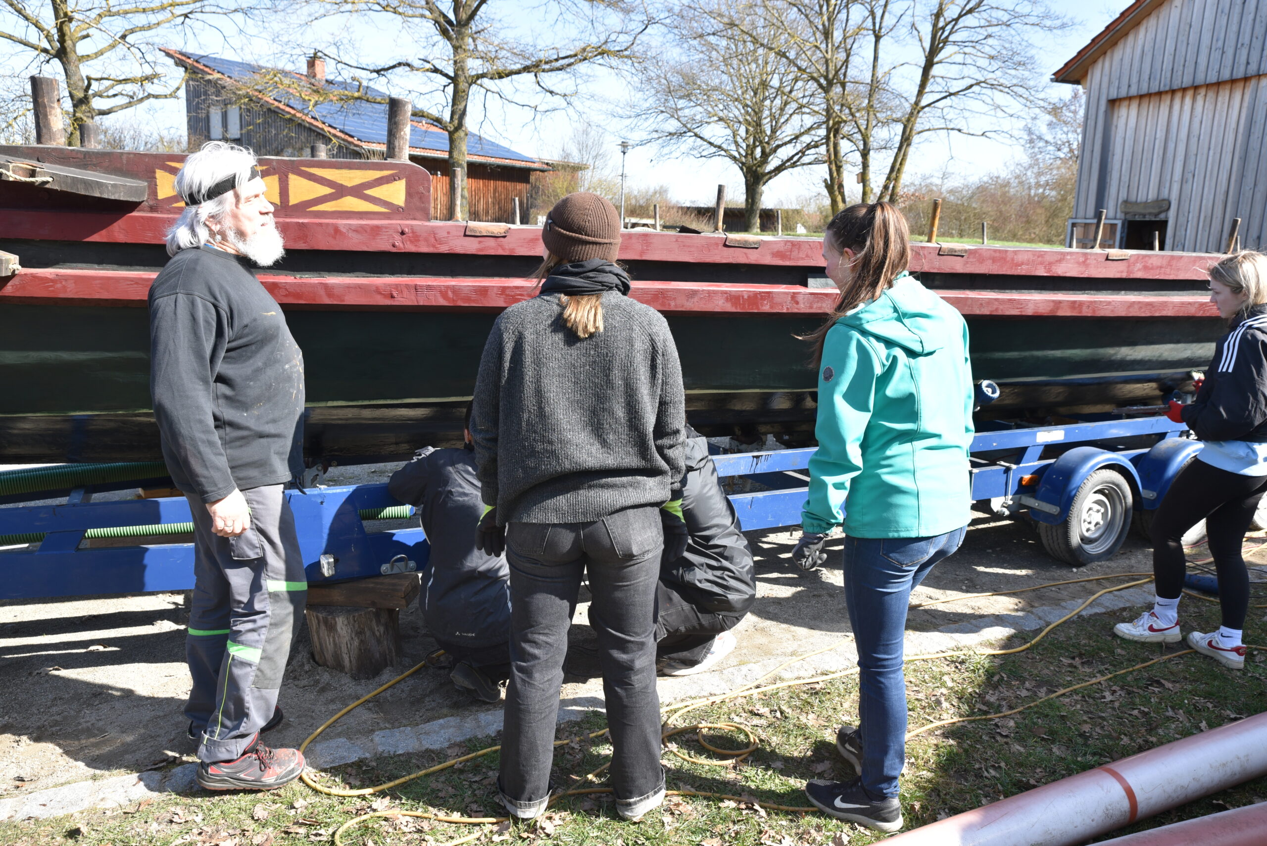 FAU chemist Dr. Marcus Speck explains the features of the encaustic paintwork to students Jule and Katharina.