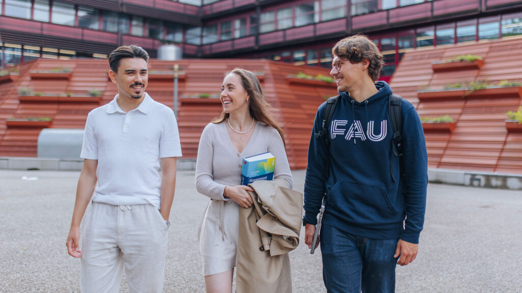 Drei Studierende gehen auf dem Campus spazieren.