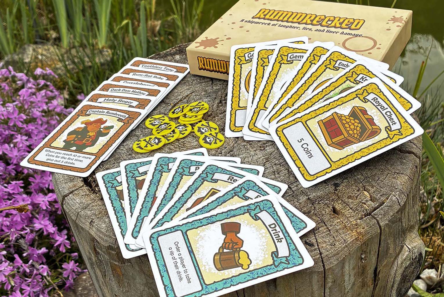 Verschiedenfarbige Karten sind zu einzelnen Decks zusammengeschlichtet, teilweise als Fächer ausgelegt, teilweise übereinander angeordnet, während inmitten Spielchips platziert sind auf einem Baumstumpf